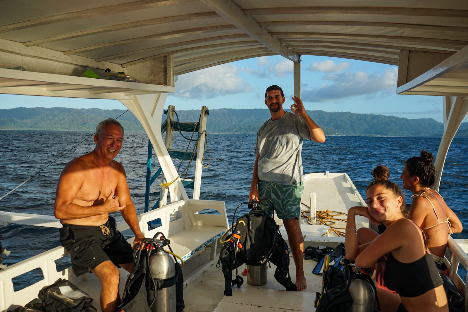 Divers smiling during a PADI Open Water dive briefing on the Sunset Divers boat in Port Barton, Palawan