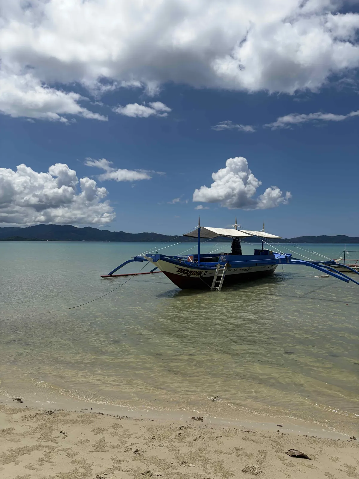 Dukatoon 2, the blue outrigger boat of Sunset Divers, in the shallow waters of Port Barton Bay, Palawan